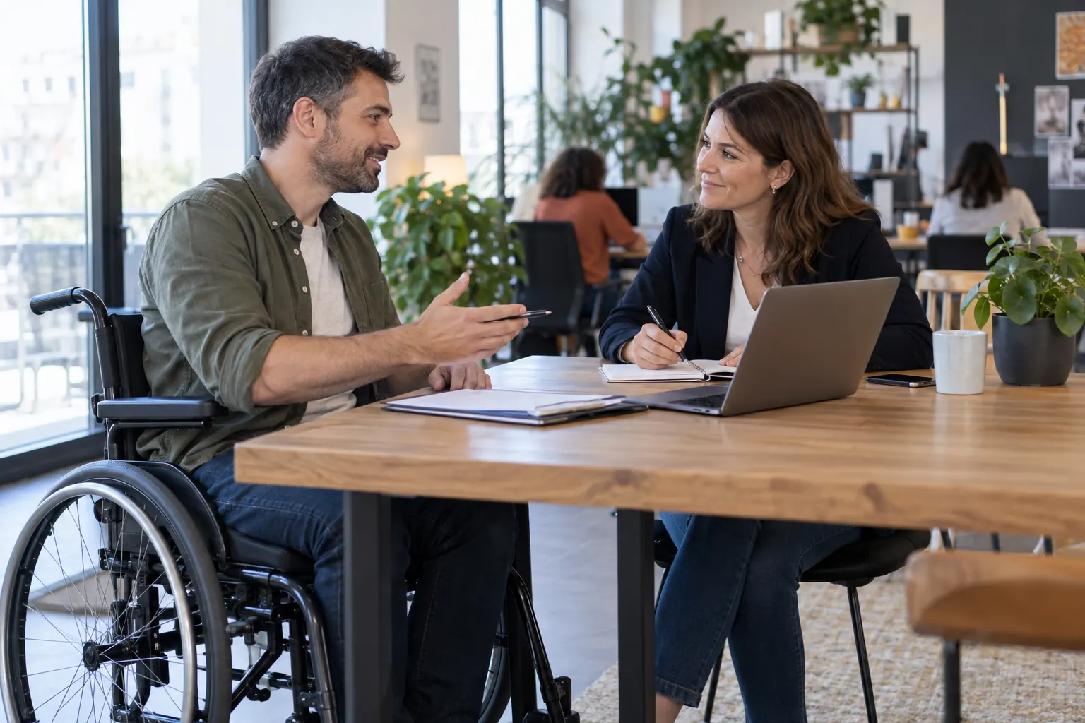 Un candidat en fauteuil roulant échange avec une conseillère emploi dans un bureau accessible