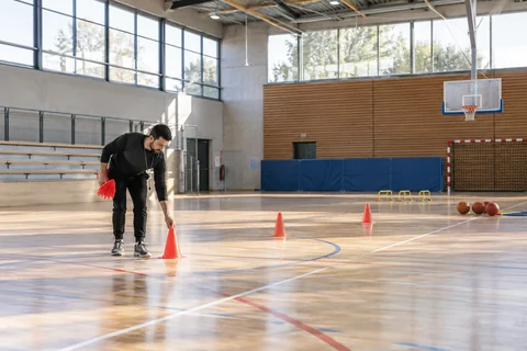 Un éducateur sportif prépare du matériel d’entraînement dans un gymnase.